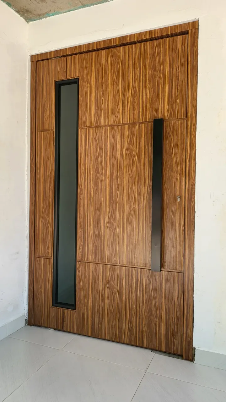 Puerta de ACM con veta de madera, ranura vertical de vidrio y tirador negro, vista de frente