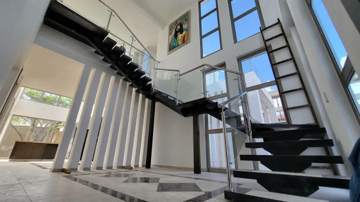 Escalera negra con baranda de vidrio y acero inoxidable, a doble altura