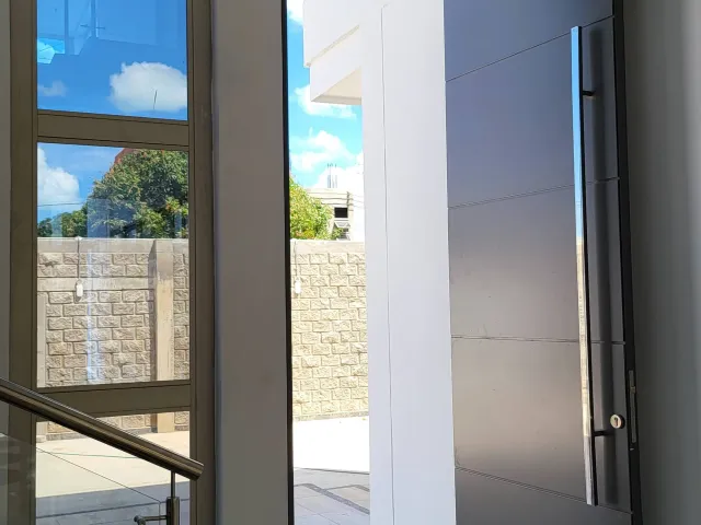 Puerta pivotante en aluminio junto a ventanal de piso a techo