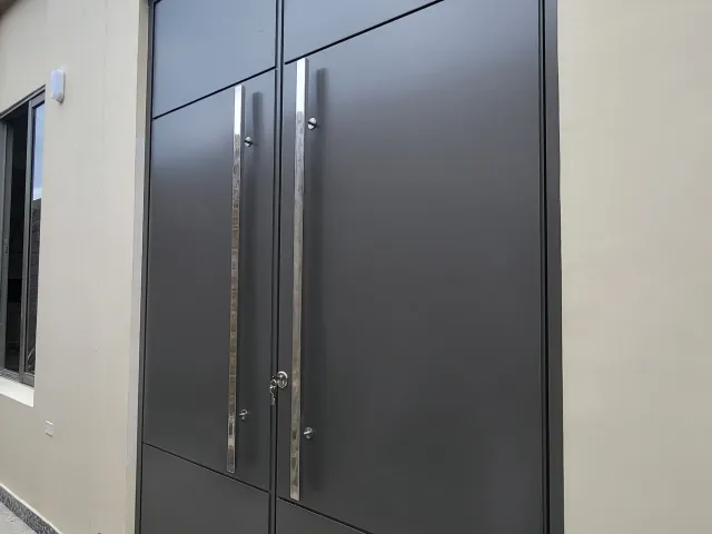 Puerta principal en aluminio con manijas en acero inoxidable