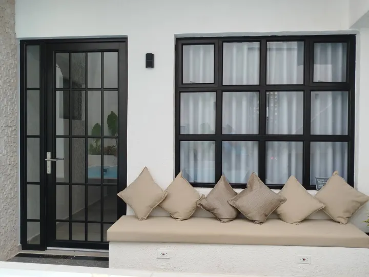 Ventanales de aluminio negro con una banca de obra y cojines debajo