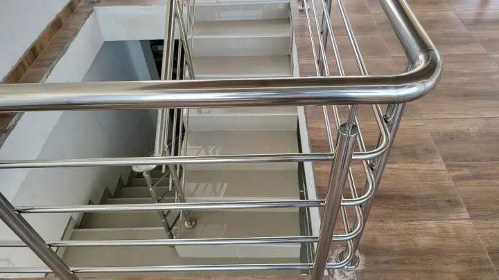 Detalle de la curva del pasamanos de acero sobre el hueco de escalera