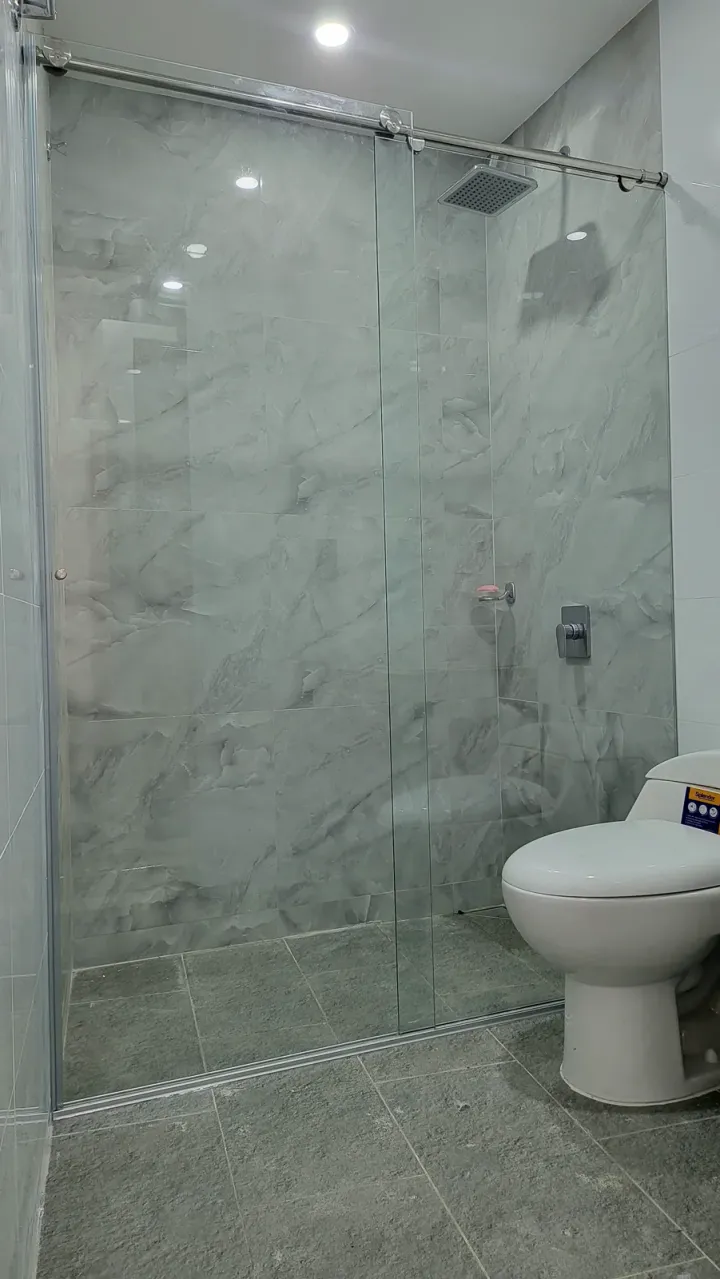 Ducha con división de vidrio a media altura y revestimiento de mármol