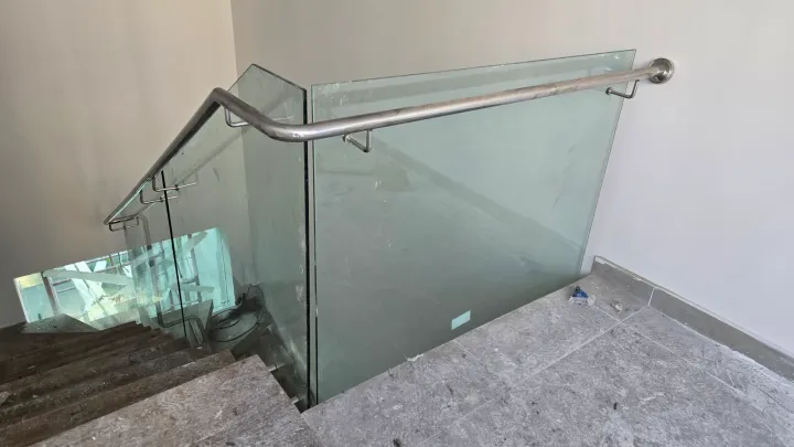 Baranda de vidrio en escalera, con pasamanos de acero curvado